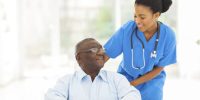 beautiful african nurse taking care of senior patient in wheelchair